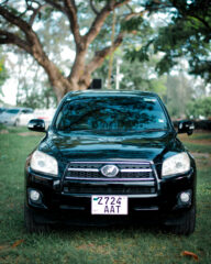 Black Toyota RAV4 SUV parked on grass under trees, front view