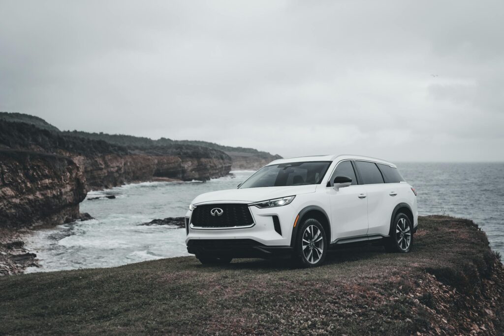 Modern white SUV on a coastal cliff road overlooking the ocean